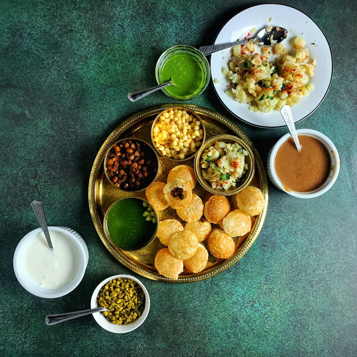 Crisp Phuchka on a brass platter with fillings and chutneys